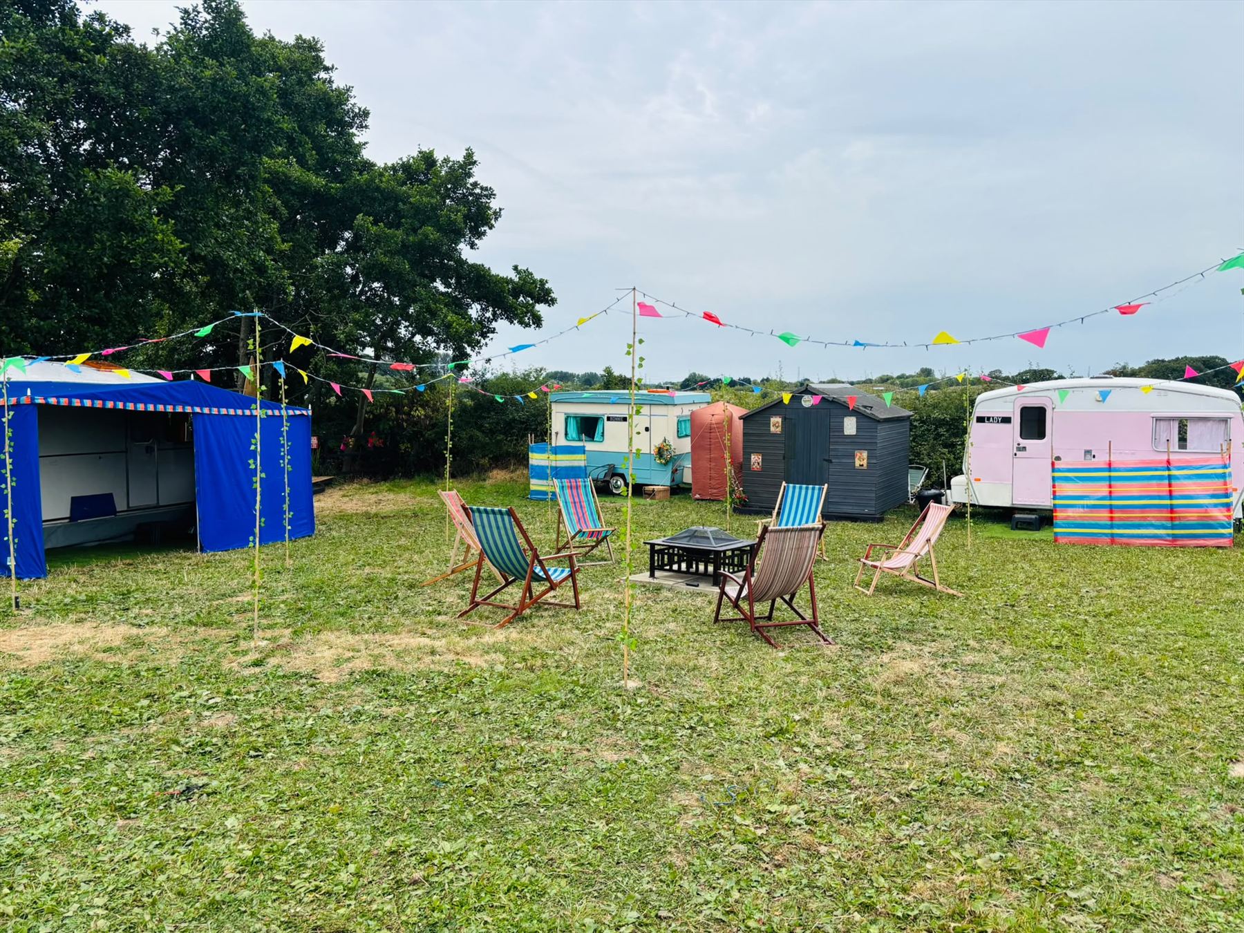 The Little Vintage Village campsite with colourful caravans, deckchairs and bunting