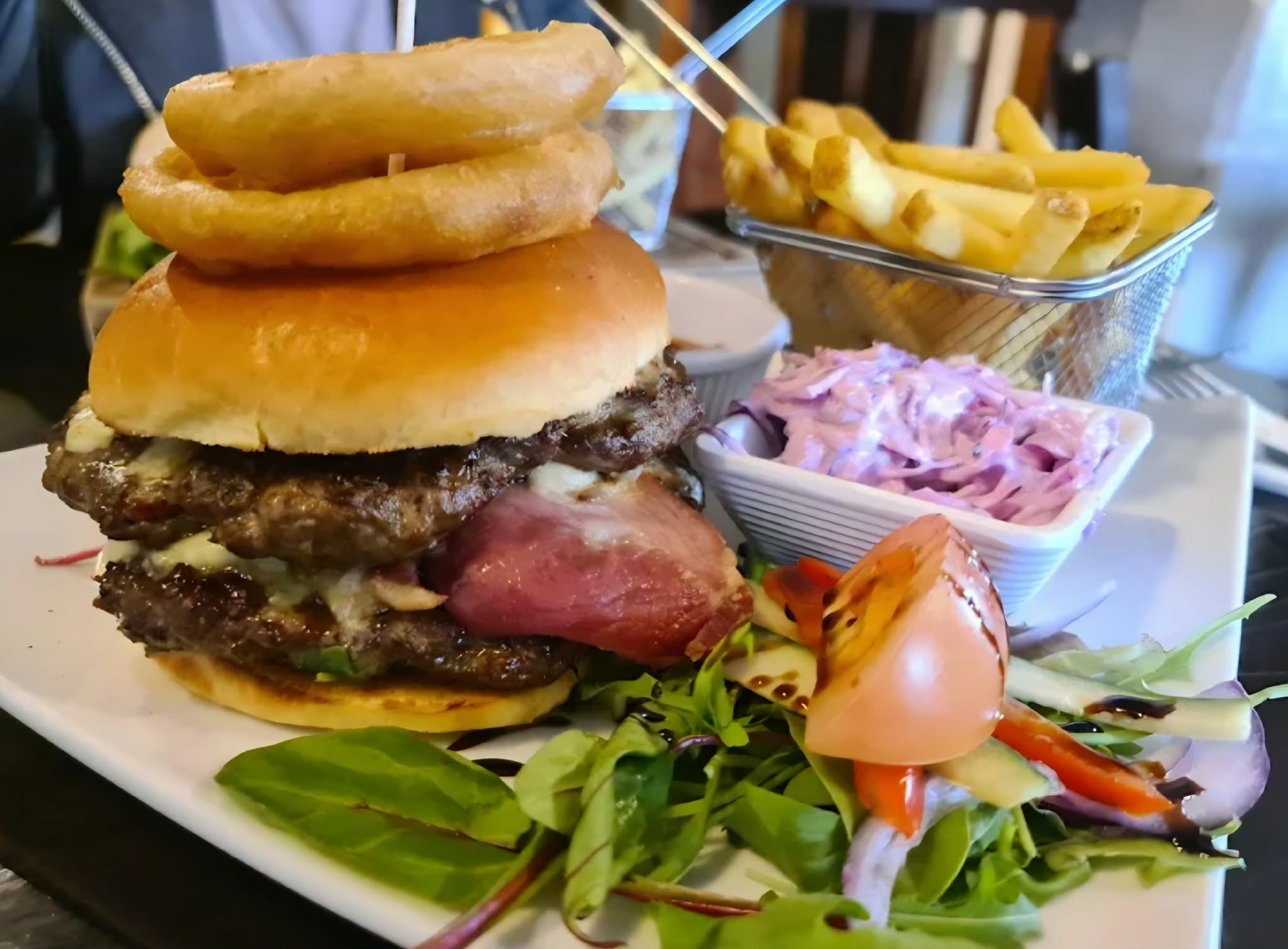 Burger with onion rings, chips, salad and coleslaw served at The Miller's Arms