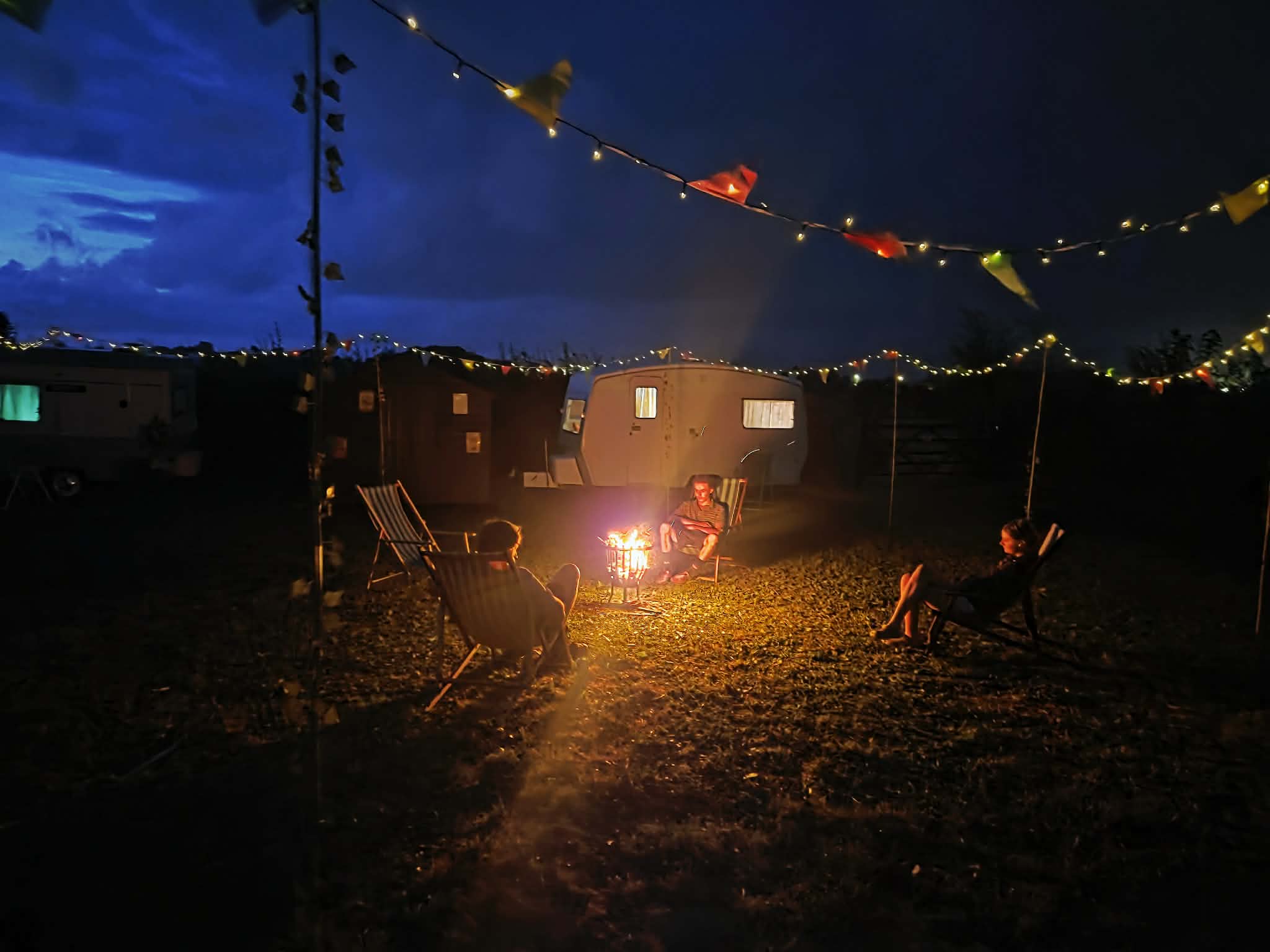 Guests relaxing around the firepit beneath festoon lights