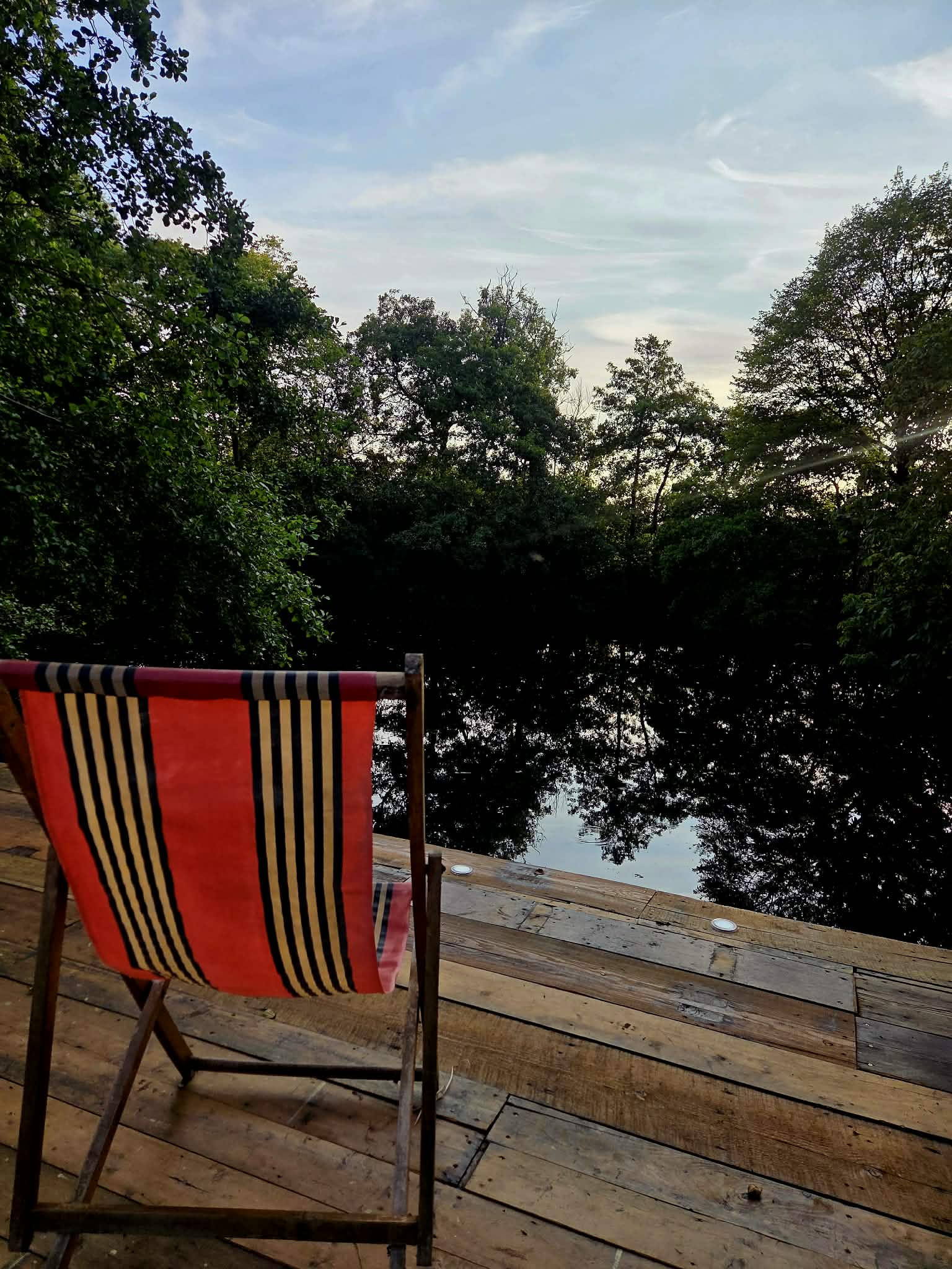 Striped deck chair overlooking the peaceful woodland pond